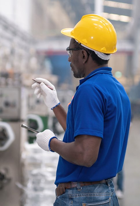 A man with safety glasses and a hardhat inspecting a factory