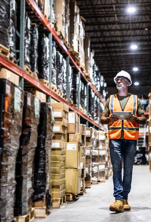 A person walking down a long hall of boxes in a warehouse