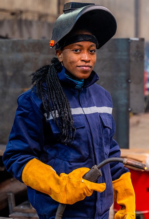 A woman welder wearing protective gear.